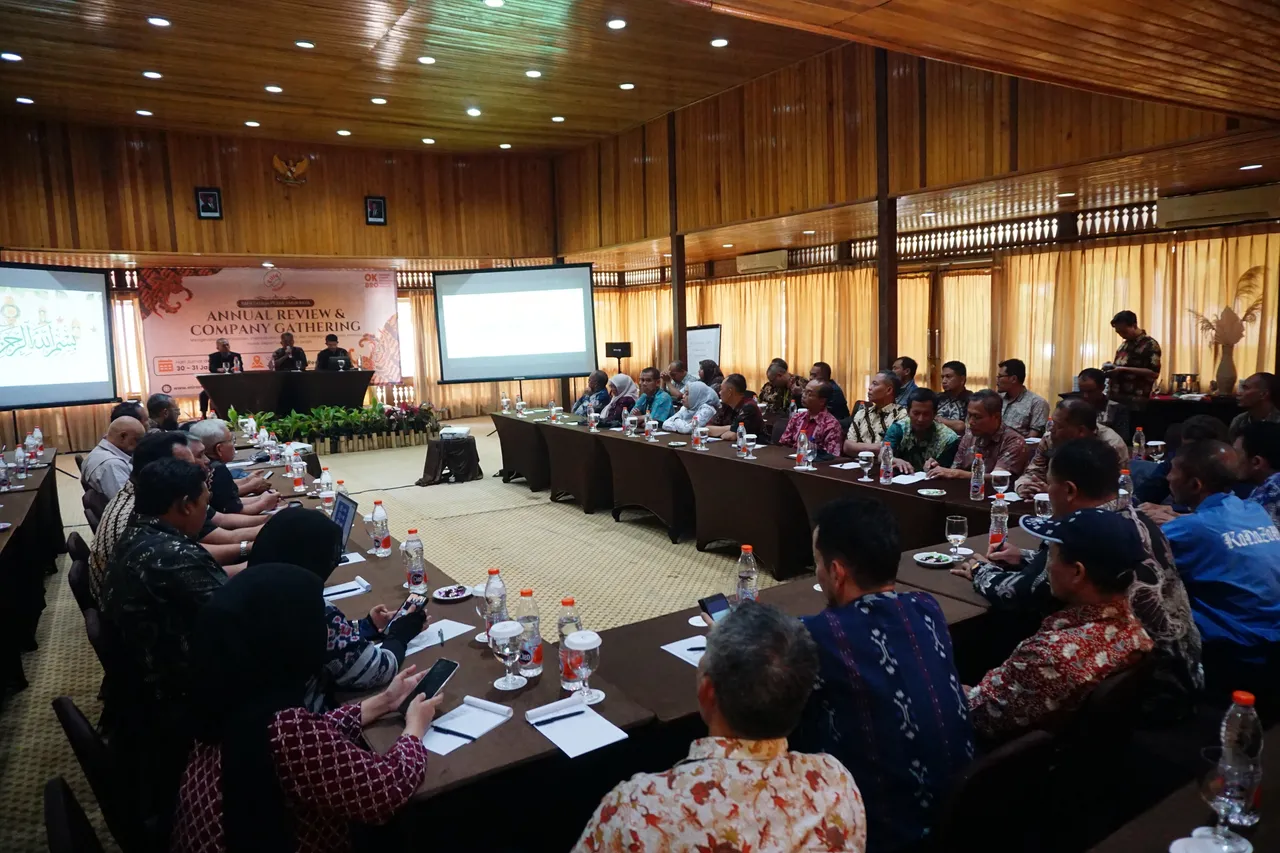 Peserta company gathering dua hari duduk mengelilingi meja panjang mengikuti sesi annual review di aula kayu
