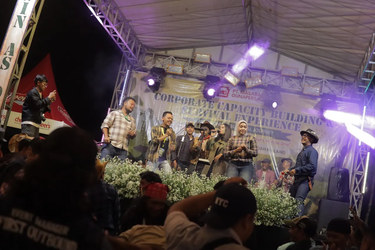 Panggung hiburan malam dengan pengisi acara bernyanyi dan peserta menonton dari bawah panggung